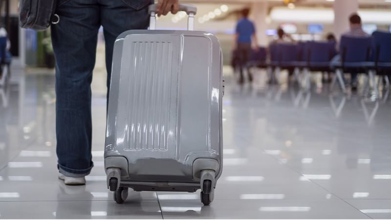 Passeggero in aeroporto con valigia trolley